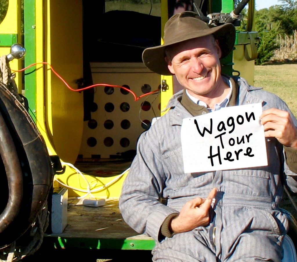 Bernie holds a sign in front of his wagon.